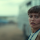 Ella Purnell stands in front of a bus.